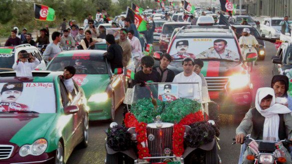Afghans in Kandahar Province parade down a main street with cars, trucks and motorcycles decorated with the colours of the Afghan flag. [Salaam Times]