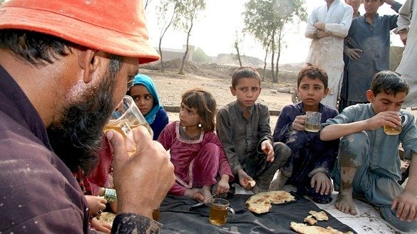 Abdur Raziq and his six children, drink tea following their work. Raziq says that, since he began working in the brick factory, he eats only dry bread with green tea for his three daily meals. [Khalid Zerai]