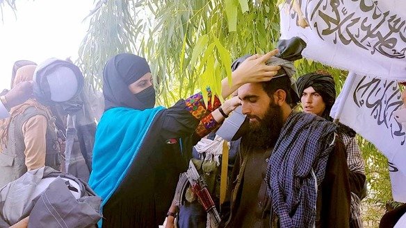 A woman places a turban on the head of a Taliban fighter as a traditional sign of respect and dignity in Nangarhar Province June 17. A number of women demanded that the militants extend the ceasefire beyond the three days of Eid ul Fitr. [Nangarhar Provincial Media Office/Facebook]