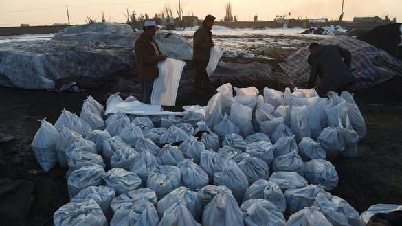 بتاریخ ۱۸ جدی، کارگران در محوطه زغال سنگ در حومه کابل، که توسط دودهای غلیظ احاطه شده،‌ کیسه های زغال سنگ را پر می کنند. [وکیل کوهسار/ خبرگزاری فرانسه]