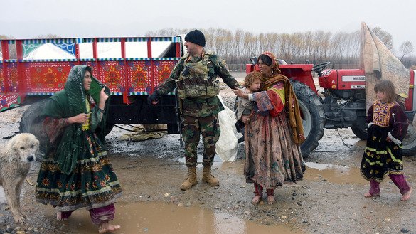 Afghan security forces March 2 help a woman and child after a flood hit their home in Arghandab District, Kandahar Province. [Javed Tanveer/AFP]