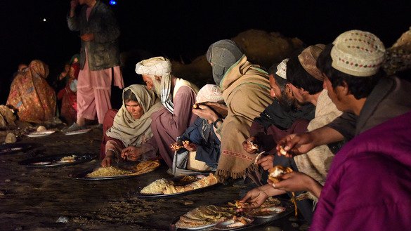 Afghans displaced by flooding eat in Arghandab District, Kandahar Province, March 3. [Javed Tanveer/AFP]