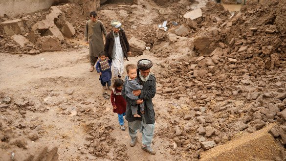 Villagers March 29 in Herat Province walk down a street covered in mud after flash flooding. [Hoshang Hashimi/AFP]