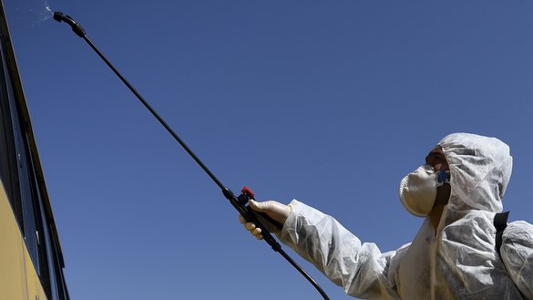 در این تصویر، یک رضاکار در جریان یک کمپاین پیشگیرانه علیه گسترش کووید-۱۹ به تاریخ ۲۸ حوت در کابل دیده می شود که، تجهیزات محافظوی پوشیده است و ضد عفونی کننده را بر یک بس اسپری می کند. [وکیل کوهسار/ای اف پی]
