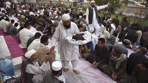 Afghan volunteers distribute dates as others wait to break their fast in Kabul on the first day of Ramadan (May 27). [Wakil Kohsar/AFP]