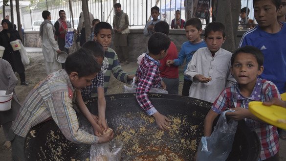 Afghan children collect rice donated by a private charity during the first day of Ramadan, May 27, in Kabul. [Wakil Kohsar/AFP]