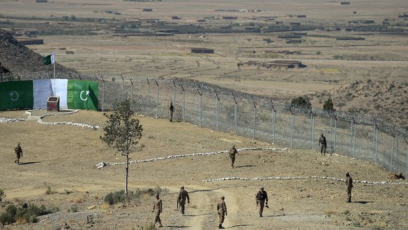 Pakistani soldiers patrol next to a new fence separating Angoor Adda, South Waziristan, and Paktika Province, Afghanistan, October 18. [Aamir Qureshi/AFP]