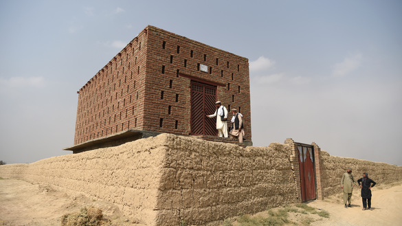 یک دهقان افغان همراه با باشنده گان محلی بتاریخ ۱۴ میزان در ولسوالی ده سبز کابل به یک اتاق خشک کردن انگور وارد می شوند. این کشمش خانه های جدید از خشت ساخته شده اند طوریکه سطح آن کانکریت می باشد. [وکیل کوهسار/خبرگزاری فرانسه]