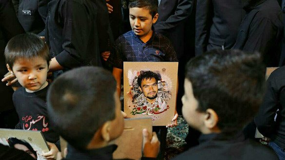 A child holds a picture of his father at a religious ceremony in Mashhad, Iran, September 20. His father was reportedly killed in Syria while fighting as part of the Fatemiyoun Division. [File]