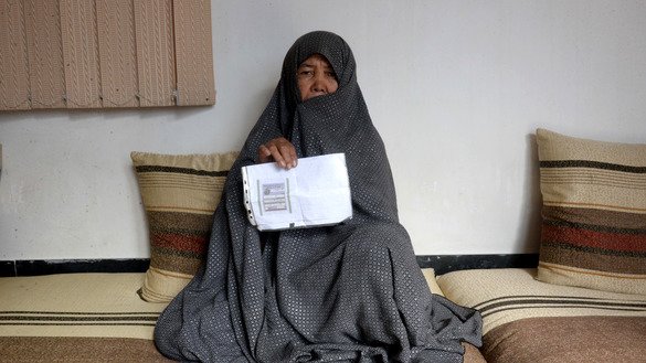 Housewife Fatimah, 55, poses for a picture October 11 at her house in Mazar-e-Sharif as she holds her tazkira indicating she is registered to vote in the upcoming parliamentary election. [Farshad Usyan/AFP]
