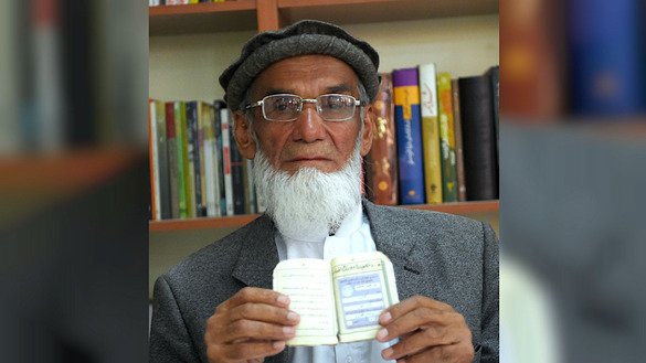 Retiree Abdul Karim, 85, poses for a picture October 11 as he holds his tazkira indicating he is registered to vote in the upcoming parliamentary election, in Kabul. [Wakil Kohsar/AFP]