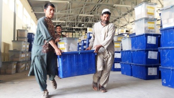 Two IEC employees carry ballot boxes at a warehouse in Herat city on October 13. [Nasir Salehi]