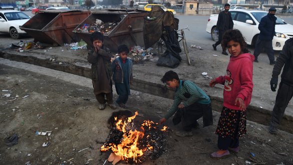 بتاریخ ۲۶ جدی، کودکان در امتداد یک سرک در کابل با سوزاندان ضایعات پلاستیکی دور یک آتش که دود غلیظی آن را احاطه کرده،‌ خودشان را گرم می کنند. [وکیل کوهسار/ خبرگزاری فرانسه]