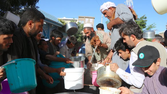 A number of Herat residents receive meals at a public feast on May 25. Citizens organise public events to help impoverished families in the month of Ramadan. [Omar]