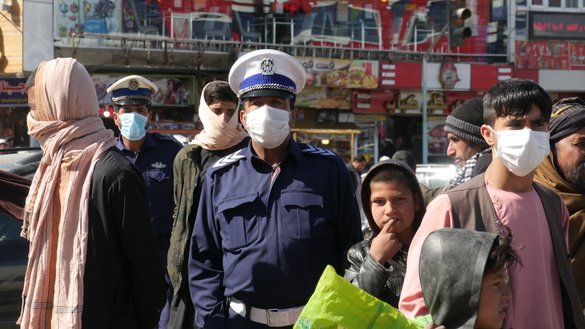 در این تصویر دیده می شود که، به تاریخ ۱۸ حوت یک افسر پولیس ترافیک و تعدادی از افغان ها ماسک می پوشند تا شیوع ویروس کورونا در شهر هرات را متوقف کنند. [عمر]