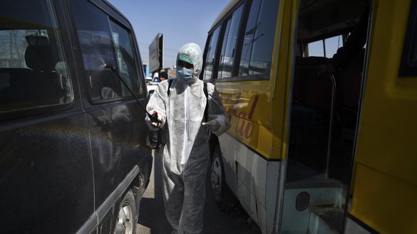 A volunteer wearing protective gear and a mask sprays disinfectant on vehicles during a preventive campaign against the spread of COVID-19 in Kabul on March 18. [Wakil Kohsar/AFP]
