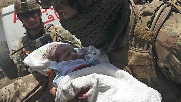 An Afghan security force member carries a newborn baby from Barchi National Hospital in Kabul, the site of a terrorist attack on May 12. [STR/AFP]