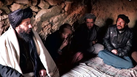 د الجزیرې انګلیسي له یوې ویډیو څخه اخیستل شوی دا عکس په نشه ییزو توکو روږدي کسان په داسې حال کې ښیي چې په هرات ولایت کې په یوه نامعلوم ځای کې د طالبانو له یوه محلي قوماندان سره ګوري.