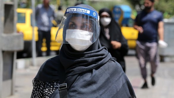 An Iranian woman wearing a face shield walks along a street in Tehran on August 9. [ATTA KENARE/AFP]