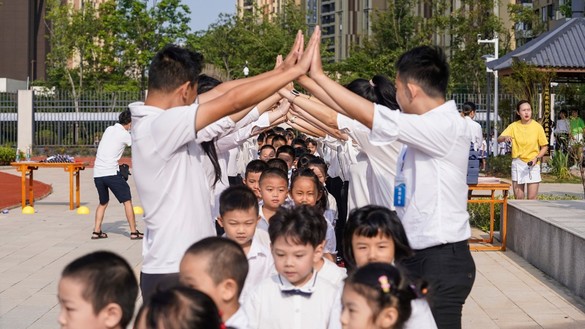 Elementary school students are welcomed by teachers as they arrive at school on the first day of the new semester in Wuhan, China, on September 1. [STR/AFP]