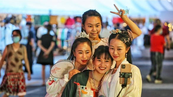 در این تصویر دیده می شود که، زنان بدون محافظت از ویروس به تاریخ ۶ سنبله در ووهان، چین عکس می گیرند. [اس تی آر/ای اف پی]