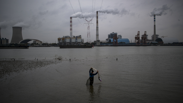 This file photo taken on February 21, 2017, shows a man fishing in the Huangpu River across from a coal-burning power plant in Shanghai. [Johannes Eisele/AFP] 