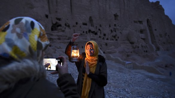 A woman poses for a picture near the empty alcove where the Shahmama Buddha -- the smaller of the two statues -- once stood during a March 9 ceremony marking the 20th anniversary of its destruction by the Taliban. [Wakil Kohshar/AFP]
