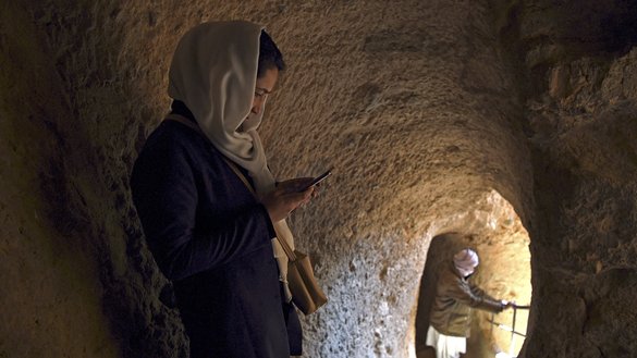 یک زن هزاره به تاریخ ۱۳ حوت در داخل یک دهلیز در محل بوداهای بامیان تیلیفون موبایل خود را نگاه می کند. این محل علاوه بر مجسمه های بزرگ، شبکه ای از غارها، معبدها و زیارتگاه های باستانی را نیز دارد. [وکیل کوهسار/ای اف پی]