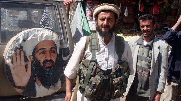 A fighter is seen standing in front of an image of Osama bin Laden, the late leader of al-Qaeda, in Rada, Yemen, January 21, 2012. [AFP Photo/STR]