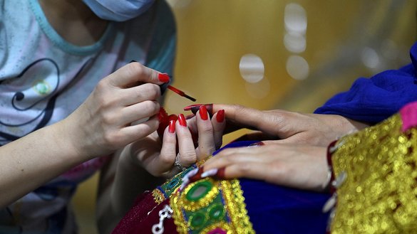 A beautician paints the nails of a Pashtun bride for her marriage at a beauty parlour in Kabul on June 10. [Adek Berry/AFP]