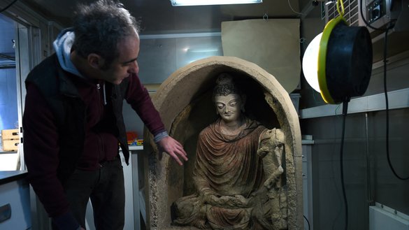 In this photograph taken on March 14, 2017, Italian restoration specialist Ermano Carbonara gestures towards a statue of Buddha at the French Archaeological Delegation to Afghanistan (DAFA) office in Kabul. [Wakil Kohsar/AFP]