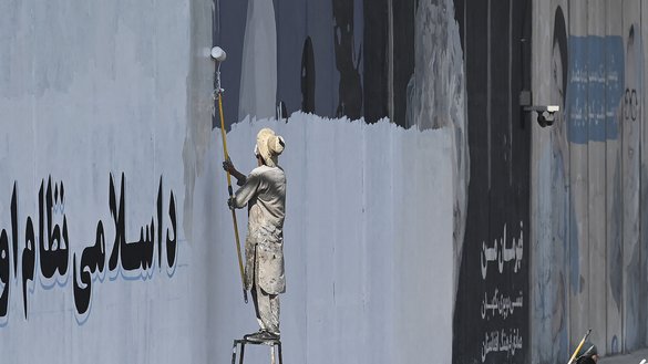 A man paints over murals on a concrete wall along a street in Kabul on September 4. Within weeks of the Taliban taking the capital, many of the street art pieces have been painted over, replaced by drab propaganda slogans as the group reimposes its austere vision on Afghanistan. [Amir Qureshi/AFP]