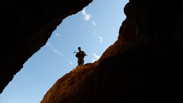 In this photograph taken on May 6, 2013, an Afghan policeman keeps watch over miners at a gold mine on a mountainside near Qara Zaghan village, Baghlan province. [Shah Marai/AFP]