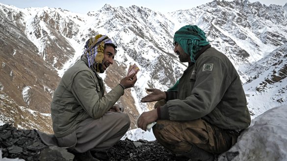 Two men haggle over the price of emeralds near the mining area on a mountain in the Mikeni Valley on January 12. [Mohd Rasfan/AFP]