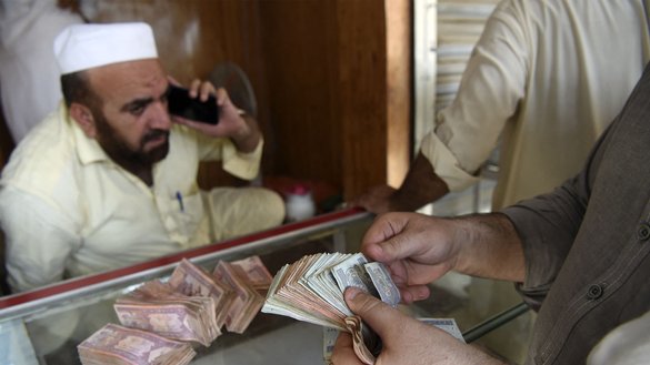 یک صراف به تاریخ ۱۶ سنبله در یک بازار پیشاور بانکنوت های افغانی را می شمارد. [عبدالمجید/ای اف پی]