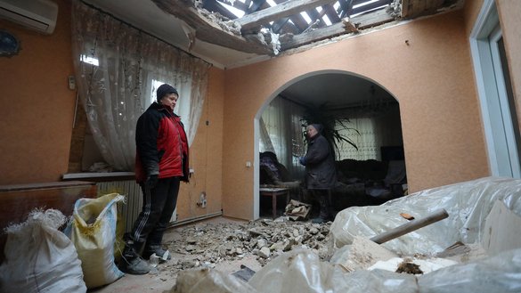 Residents of the Ukrainian-controlled village of Stanytsia Luhanska, Luhansk region, clean up debris from their home after shelling by Russia-backed separatists on February 18. [Aleksey Filippov/AFP]