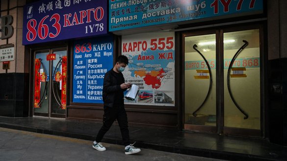 A man walks past a store advertising cargo shipping to Russia and other countries, along a street in Beijing on March 4. [Hector Retamal/AFP]