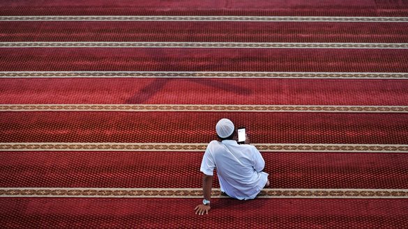 یک مرد به تاریخ ۱۷حمل در یک مسجد در اندونیزیا یک نسخه دیجیتالی قرآن کریم را روی تیلیفون خود می خواند. [چایدیر محی الدین/ای اف پی]
