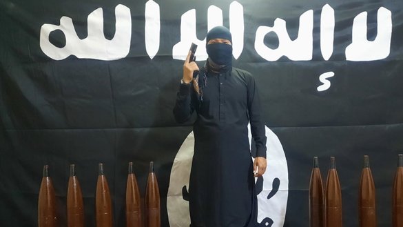 A member of ISIS poses next to shells in a picture posted as part of ISIS's claim of an April 18 attack on Uzbekistan. [File]