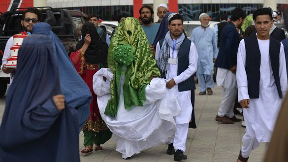یک زوج افغان بعد از مراسم ازدواج گروهی به تاریخ ۲۳ جوزا در بیرون از تالار عروسی در کابل قدم می زنند. [ساحل آرمان/ای اف پی]