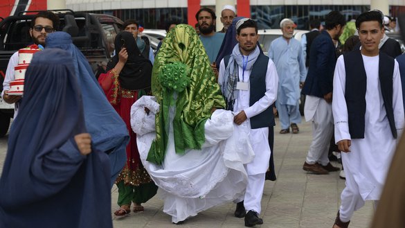 An Afghan couple walks outside the wedding hall after a mass marriage ceremony in Kabul on June 13. [Sahel Arman/AFP]