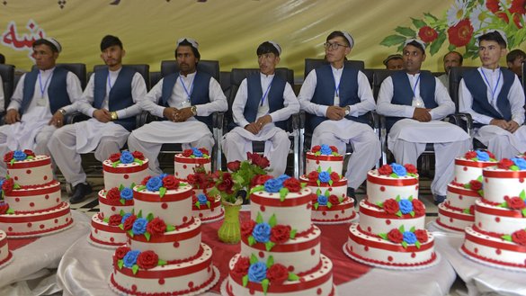 Grooms sit inside a wedding hall as they wait for the start of a mass marriage ceremony in Kabul on June 13. [Sahel Arman/AFP]