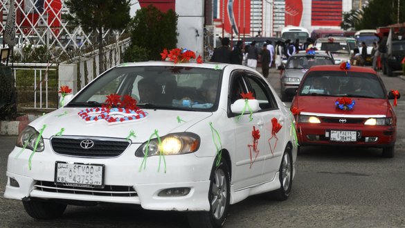 Decorated cars carrying Afghan couples leave the wedding hall after a mass marriage ceremony in Kabul on June 13. [Sahel Arman/AFP]