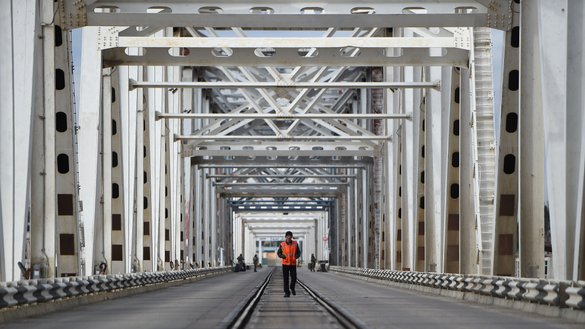 An employee of an Afghan train line walks along a rail track in the centre of the Afghanistan-Uzbekistan Friendship Bridge in Hairatan, Balkh province, Afghanistan, on February 9, 2019. [Farshad Usyan/AFP]
