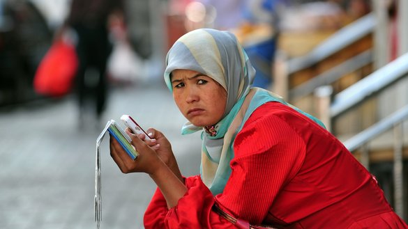 یک زن مسلمان در حال استفاده از تلیفون همراه خود در سینکیانگ چین دیده می شود. [فردریک جی براون/ خبرگزاری فرانسه]
