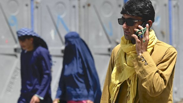 A man speaks on his mobile phone along a road in Kabul on July 21, 2021. [Sajjad Hussain/AFP]
