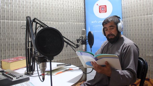 یک معلم داوطلب به تاریخ ۲۷ حمل در استودیوی رادیو صدای بادغیس در شهر قلعه نو ولایت بادغیس یک کتاب مکتب می خواند. [احمد جواد/سلام تایمز]