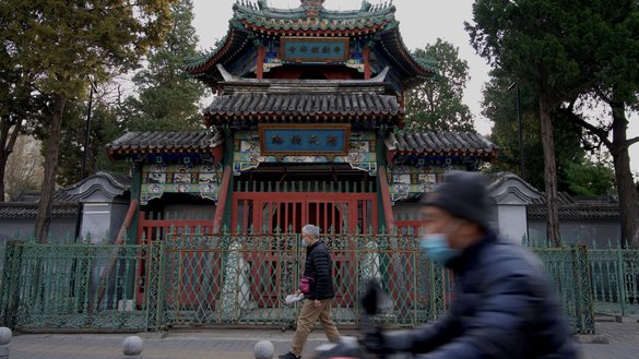 Men walk past the closed Niujie Mosque in Beijing on April 3, 2022. China is destroying any Arabic and Islamic style architecture of mosques, such as minarets and domes, as part of the government's 'sinicisation' plan. [Noel Celis/AFP]