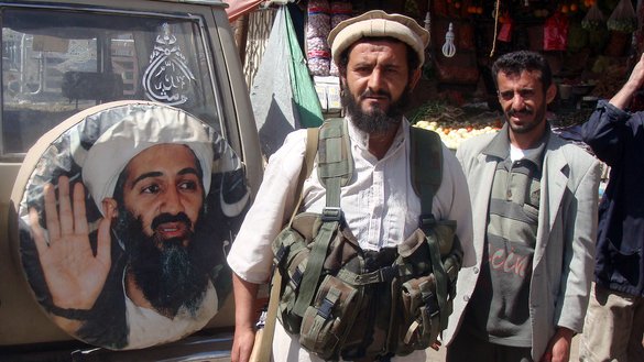 یک جنگجو به تاریخ ۱ دلو سال ۱۳۹۰ در مقابل تصویری از اسامه بن لادن، رهبر فقید القاعده، در رداع، یمن ایستاده است. [عکس از خبرگزاری فرانسه/اس تی آر]