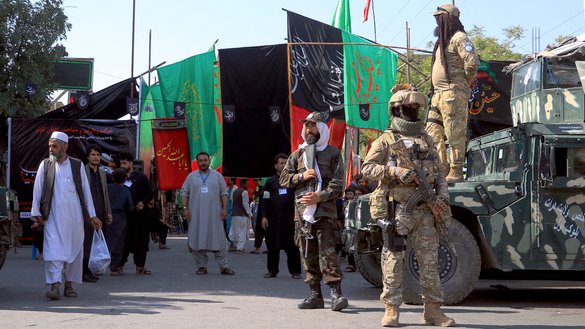 منسوبین امنیتی در حالی که ساکنان شهر به تاریخ ۲۵سرطان، یک روز قبل از عاشورا در امتداد یک سرک در هرات قدم می زنند، از آنها نگهبانی می کنند. شاخهء خراسان داعش بسیاری اوقات جوامع شیعه را هدف قرار می دهد. [محسن کریمی/ خبرگزاری فرانسه]
